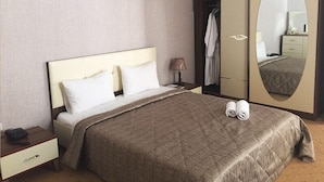 Habitación de hotel con cama, mesita de noche, lámpara, armario y espejo.