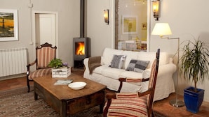 Een gezellige woonkamer met een open haard, een bank, een salontafel en een lamp.