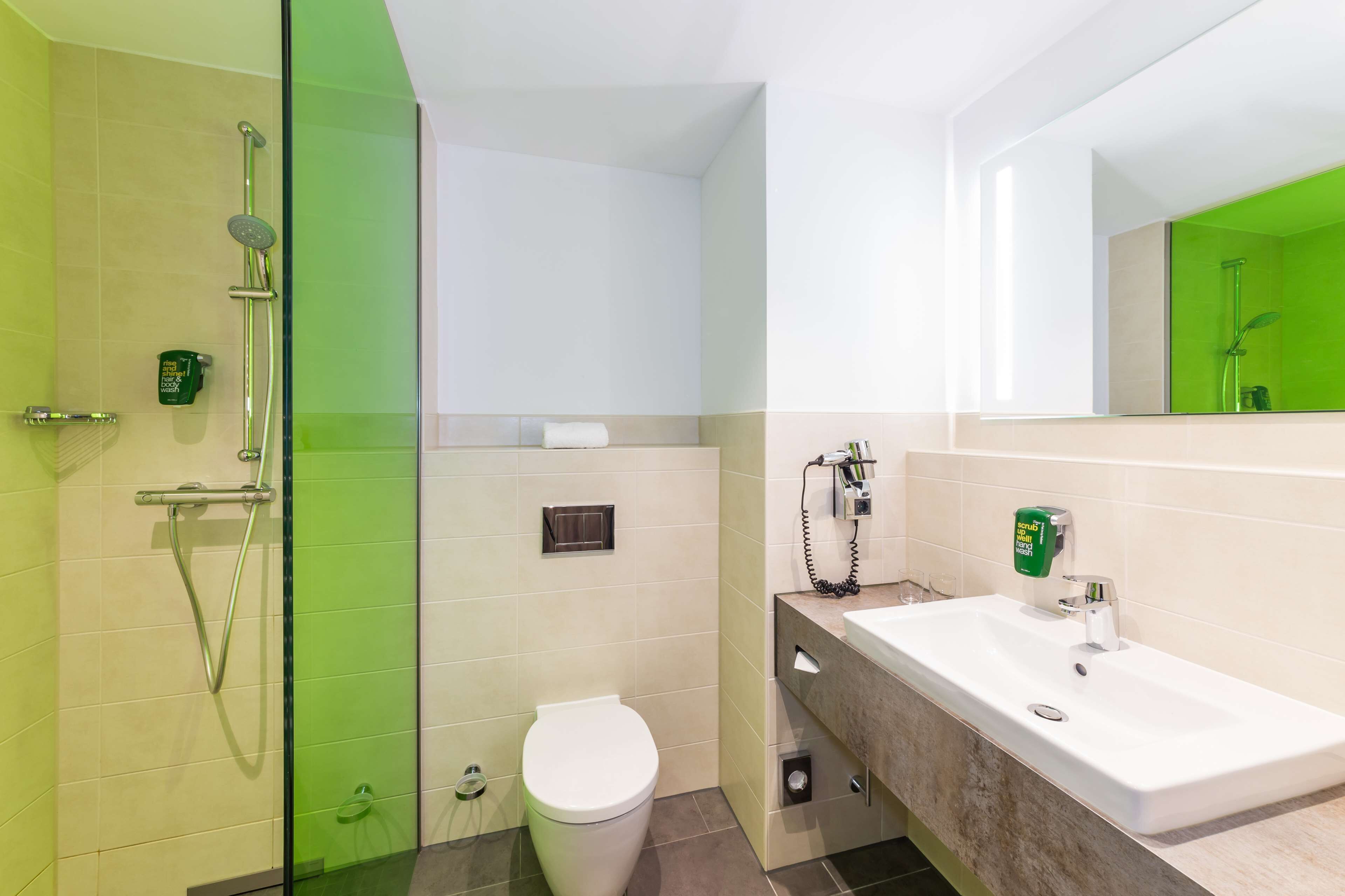 Une salle de bain moderne avec une douche à parois de verre, des toilettes blanches et un lavabo avec un miroir.