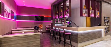 A modern bar area with a counter, bar stools, and shelves of bottles.