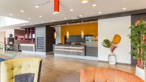 Eine moderne Lobby mit Empfangstresen, Sitzgelegenheiten und einer Treppe.