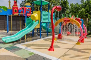 Un parque infantil con tobogán, estructuras para escalar y zona de juegos acuáticos.