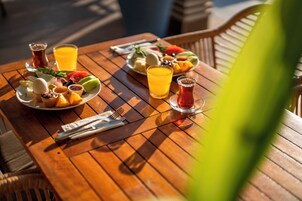 Una mesa de madera dispuesta con platos de fruta, vasos de jugo de naranja y un vaso de té.