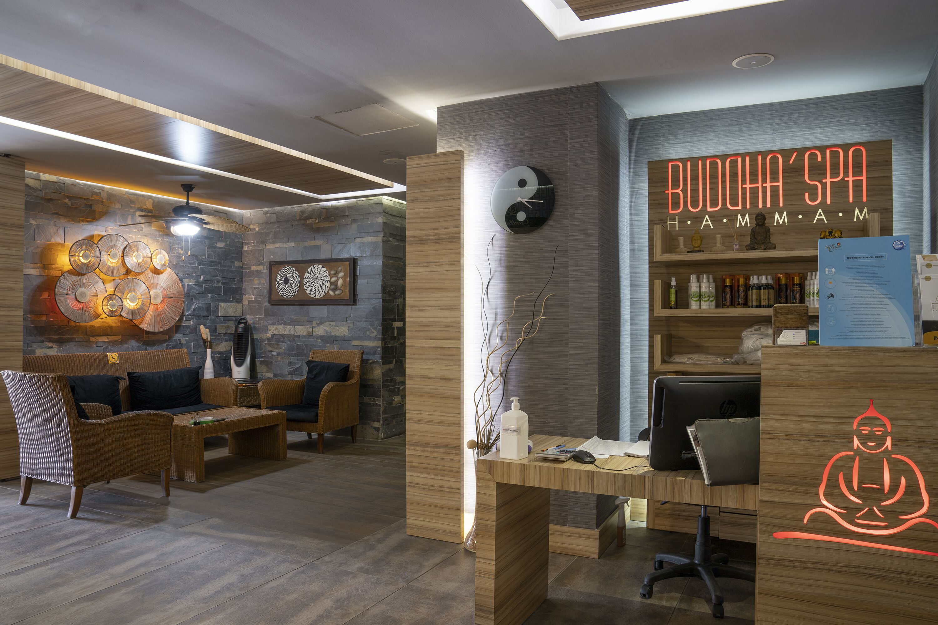 Un interior moderno con un mostrador de recepción, mobiliario de madera y una estatua de Buda.
