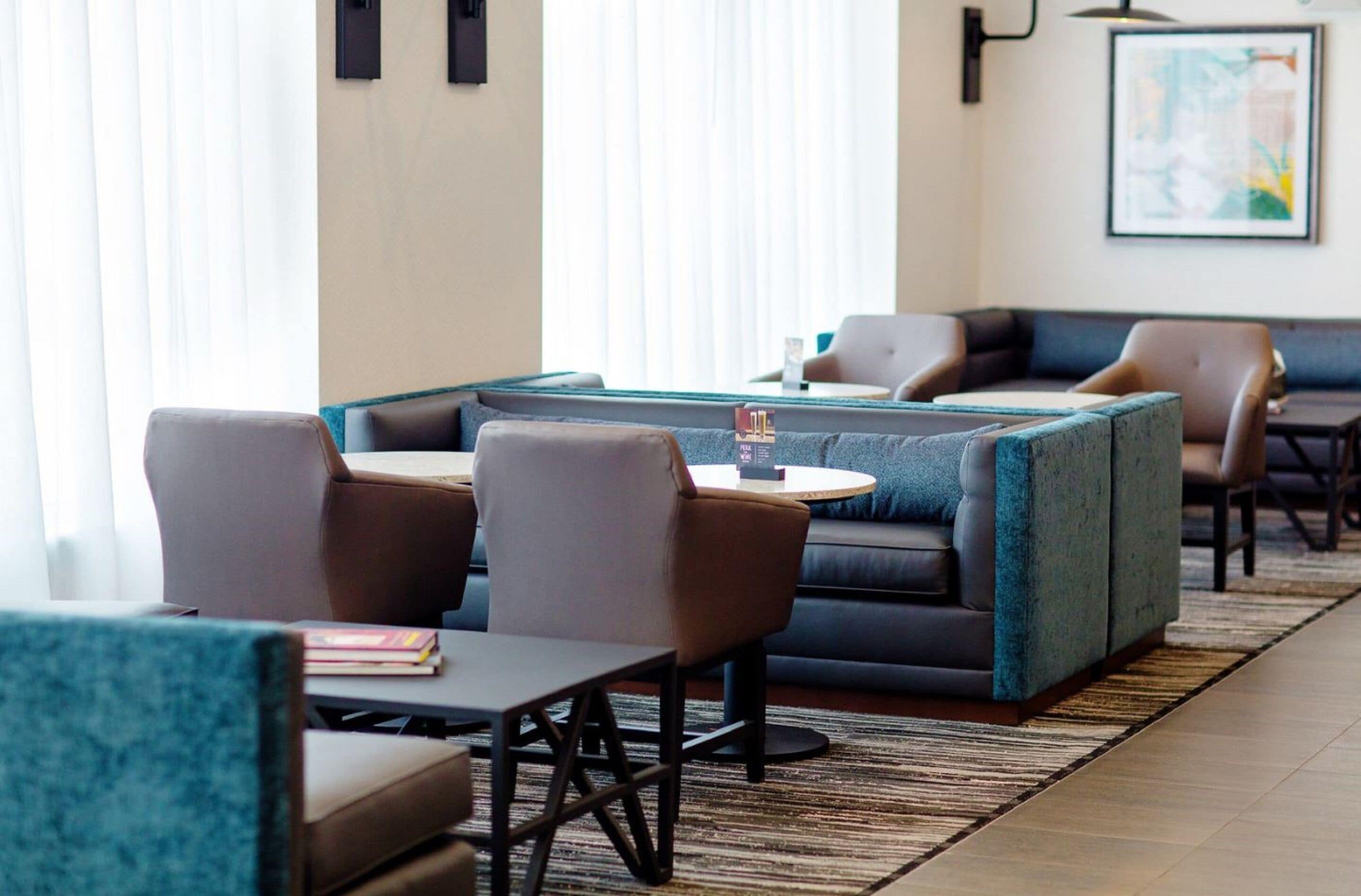 A modern hotel lobby with seating areas, a coffee table, and a framed artwork on the wall.