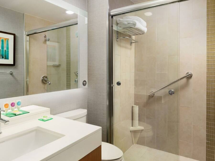 A modern bathroom with a glass-enclosed shower, a white sink with a chrome faucet, and a toilet.
