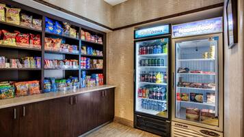 A snack and beverage vending area with shelves stocked with various snacks and a refrigerated section for cold drinks and frozen food.