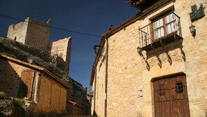 Une rue pavée dans une ville historique, bordée de bâtiments en pierre, avec une porte en bois et un balcon orné de balustrades en fer forgé.