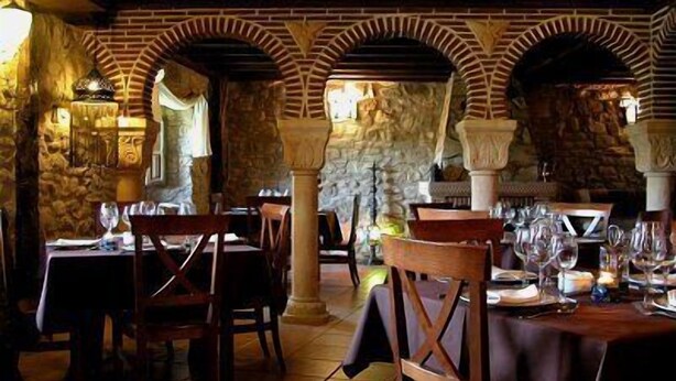 Un restaurant avec des arches en briques, des tables et des chaises en bois.