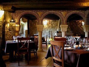 A restaurant with brick arches, wooden tables, and chairs. - El Mirador de Almanzor (Calatanazor)