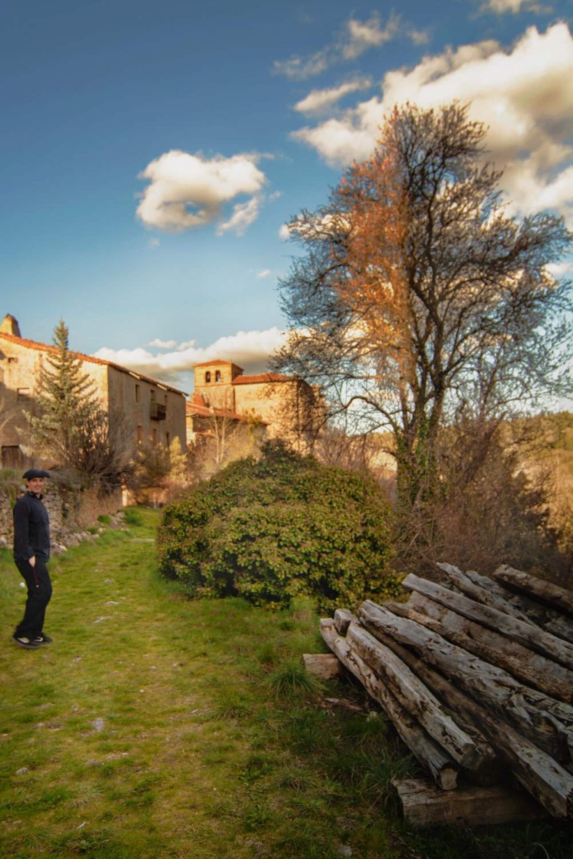 A rustic outdoor setting with a pathway leading to a building with a stone facade and a bell tower.