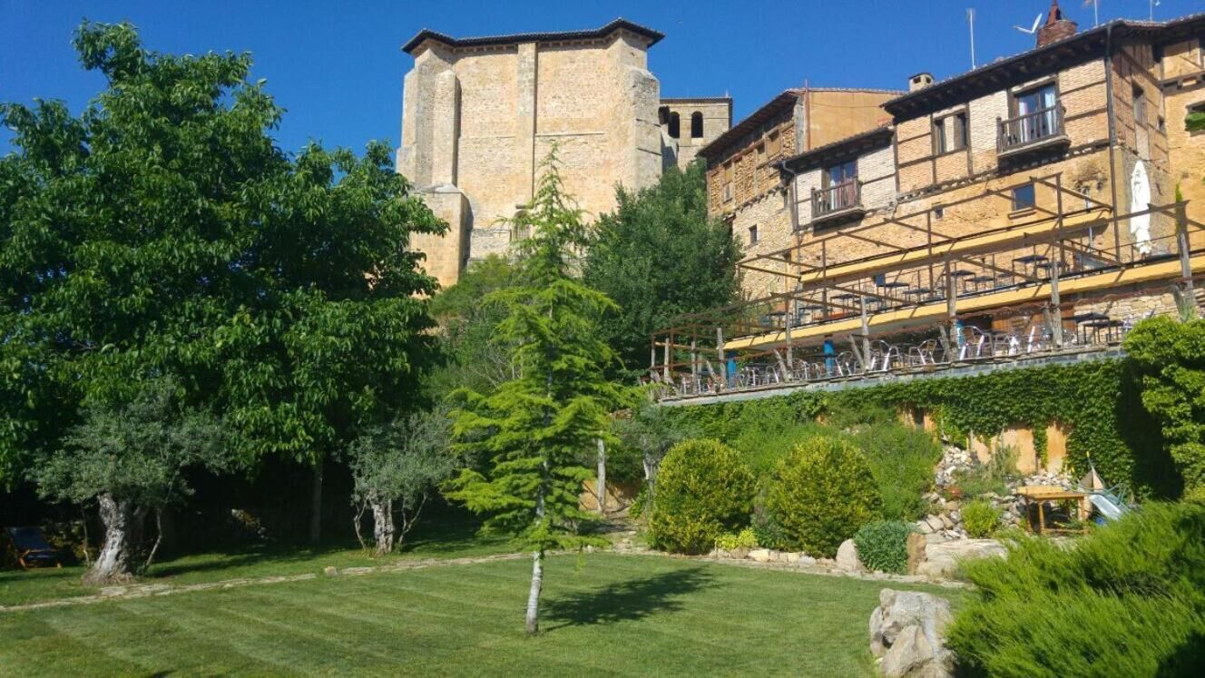 A courtyard with a stone tower, lush greenery, and a building with scaffolding.