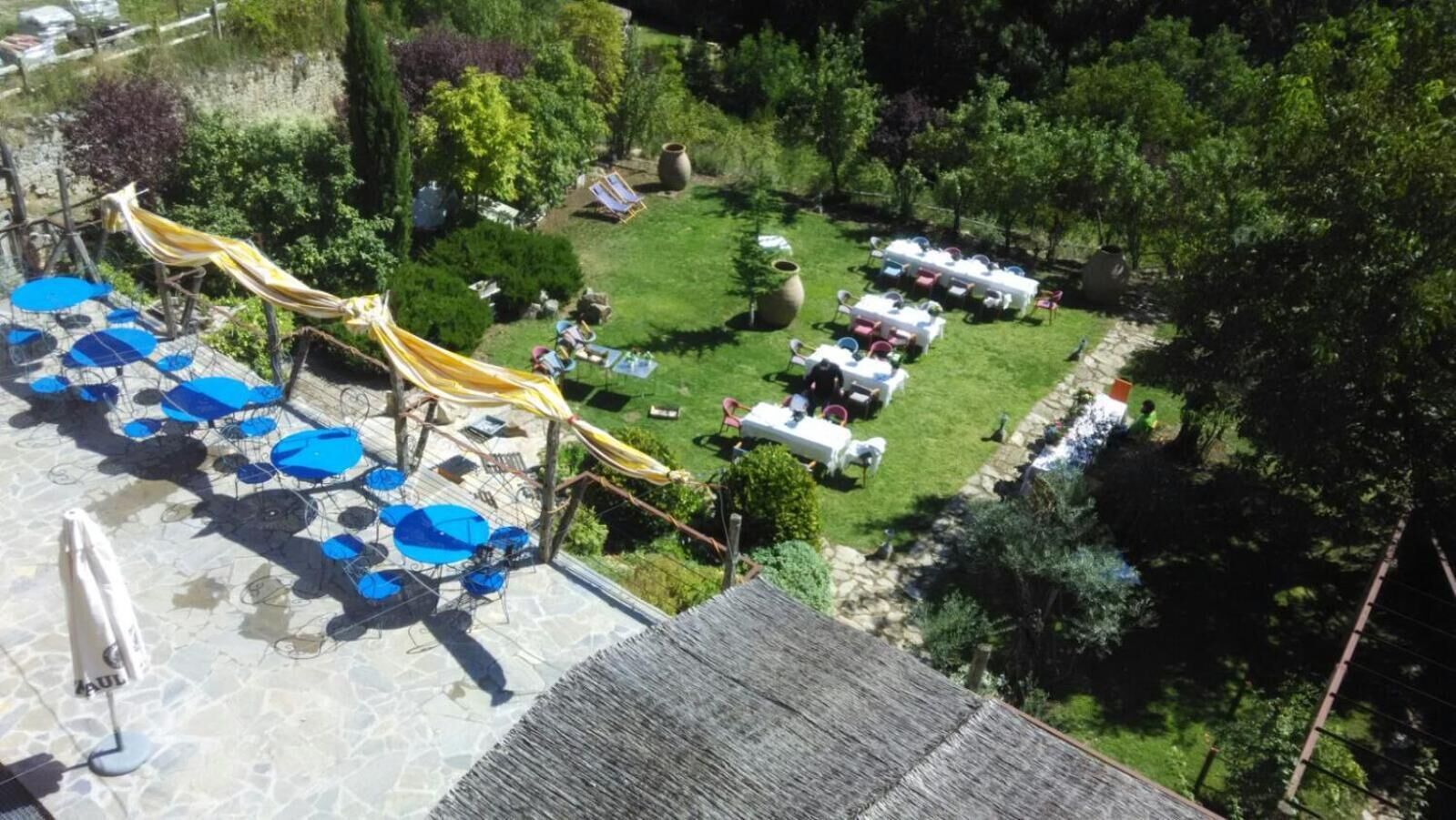 Una terraza en la azotea con sombrillas azules, un tobogán amarillo y mesas blancas dispuestas para comer.