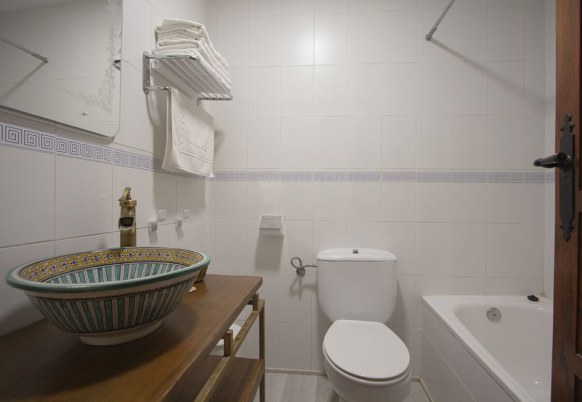 Un baño con tocador de madera, lavabo, inodoro y bañera.