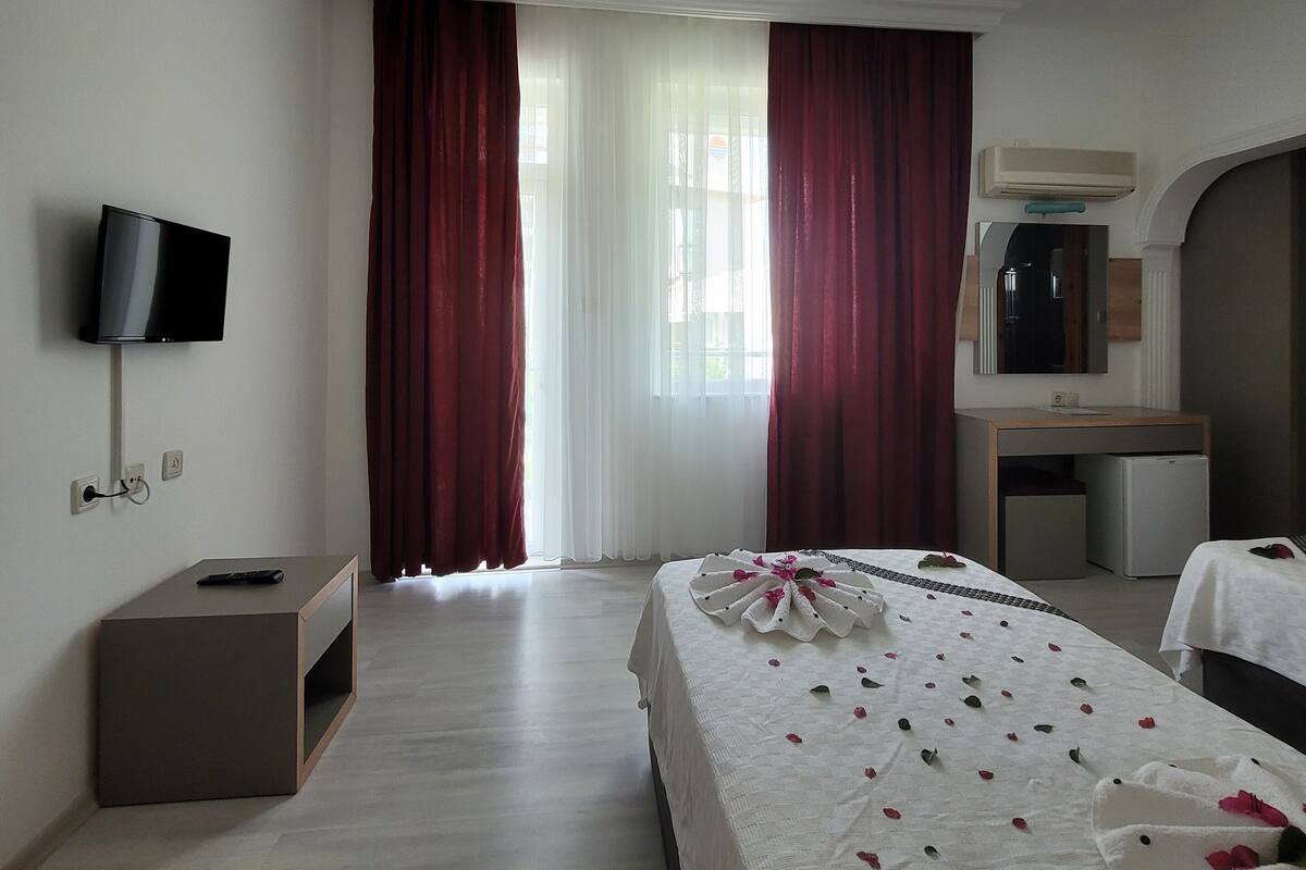 Una habitación de hotel con cama, televisión, escritorio y espejo.