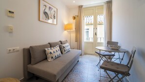 Een woonkamer met een bank, een tafel met een schaal, een lamp en een lijst met een foto aan de muur.