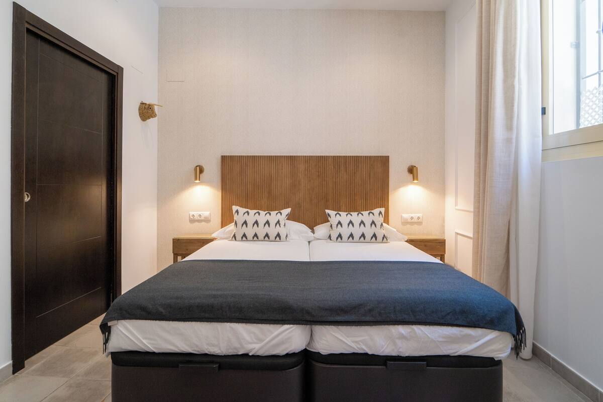 A modern bedroom with a large bed, two bedside tables, and a wooden headboard.