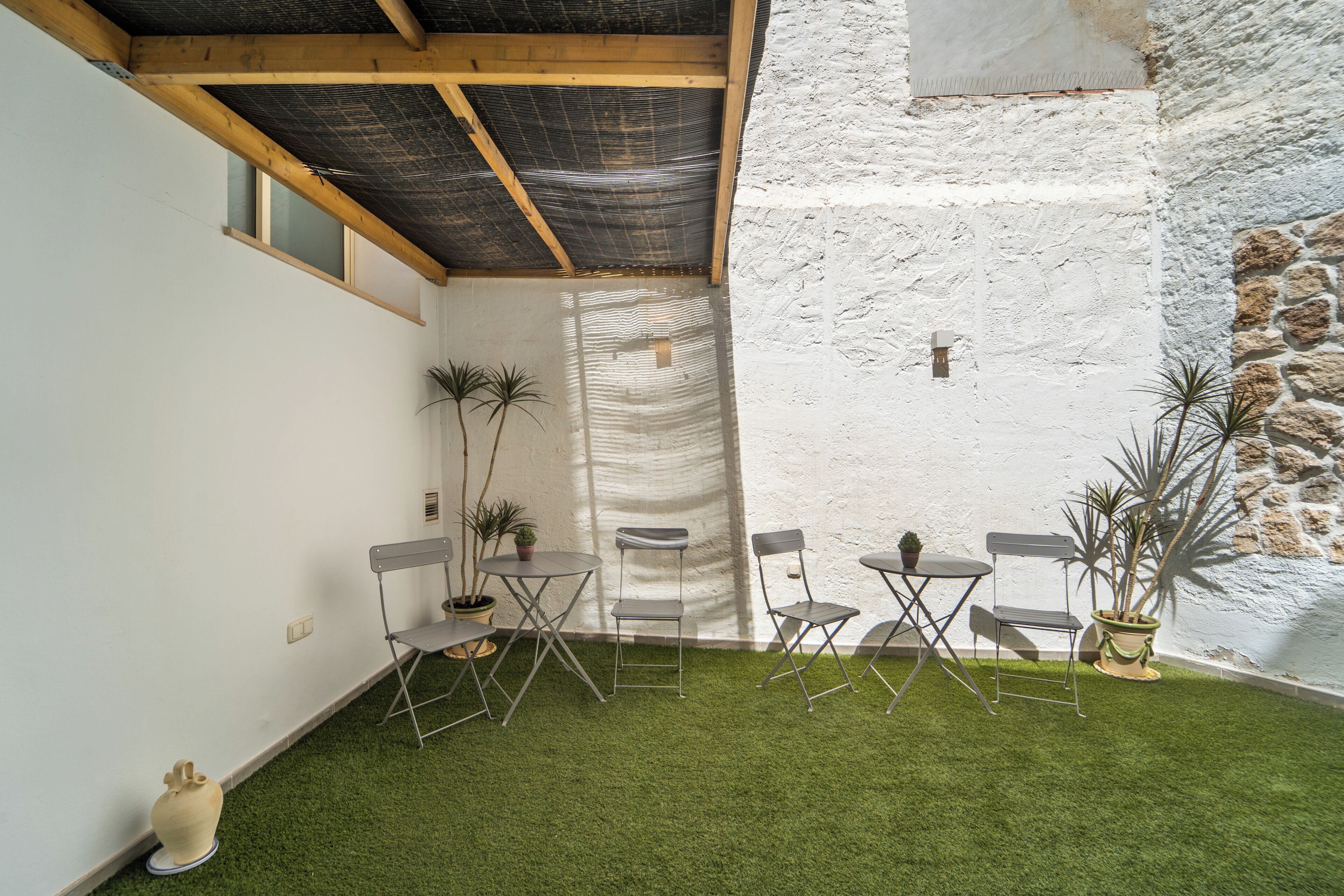 A courtyard with artificial grass, a stone wall, and a wooden ceiling.