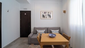 Een moderne woonkamer met een grijze bank, een houten eettafel en een kunstwerk in een lijst aan de muur.