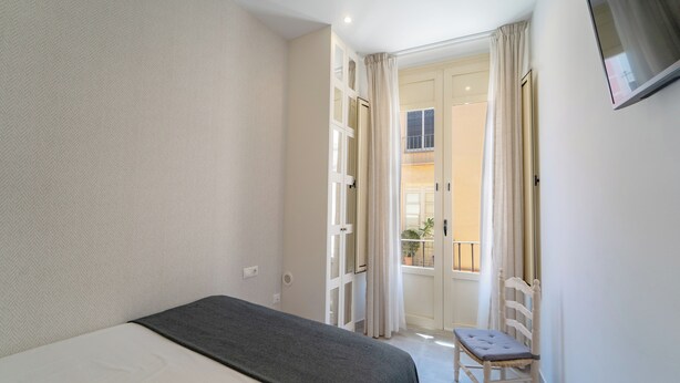 Een slaapkamer met een bed, een stoel en een openslaande balkondeur.