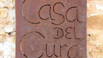 A sign with the text "Casa del Cura" on a stone wall background.