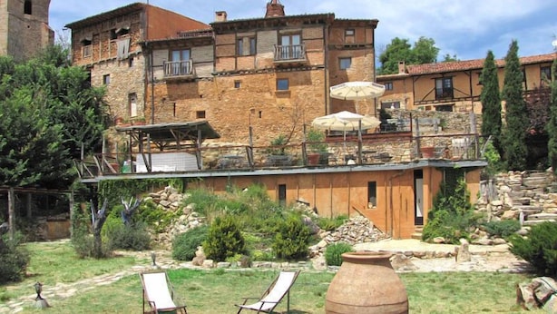 A rustic stone building with a terrace, outdoor seating, and a garden.