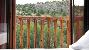 A room with a large window offering a view of a rocky hillside and greenery.