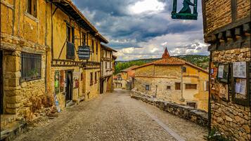 Una calle adoquinada flanqueada por edificios de piedra tradicionales, algunos con carteles que indican negocios y alojamientos locales.