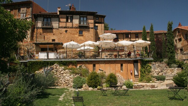 A courtyard with outdoor seating and a stone building with multiple windows and balconies.