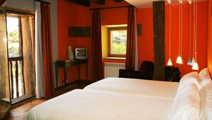A bedroom with a large bed, a television on a small table, and a window with curtains.