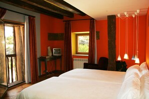 A bedroom with a large bed, a television on a small table, and a window with curtains.