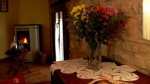 Ein gemütliches Zimmer mit Kamin, einem Tisch mit Spitze und einer Blumenvase.