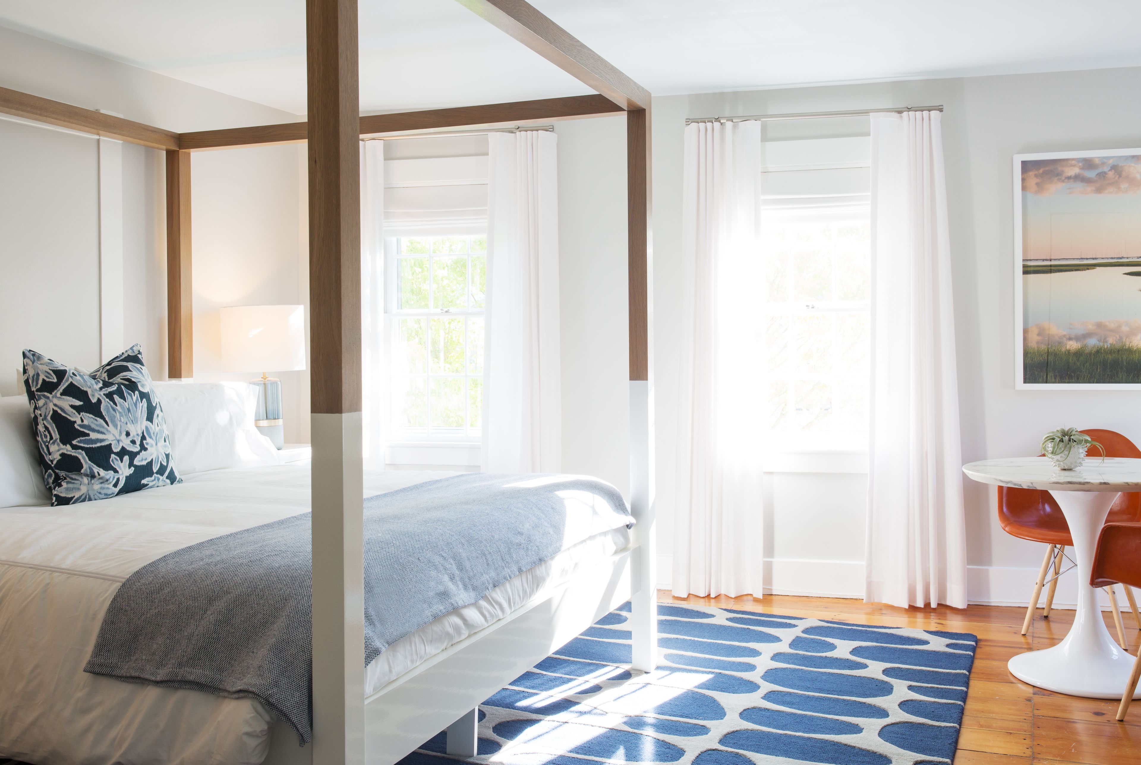 A bedroom with a large bed, a bedside table, a chair, and a window with curtains.