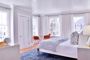 Un dormitorio con cama, escritorio, silla y ventana con cortinas.
