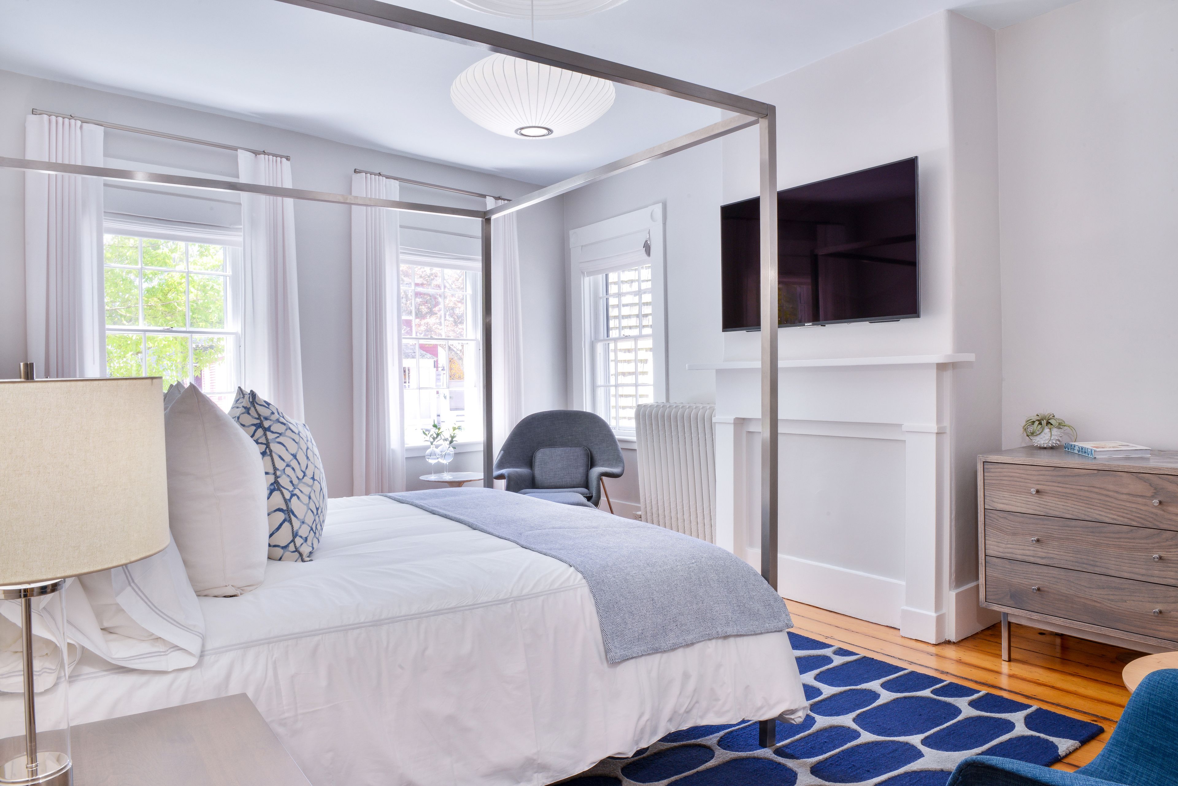 Een moderne slaapkamer met een bed, een stoel, een televisie en een dressoir.