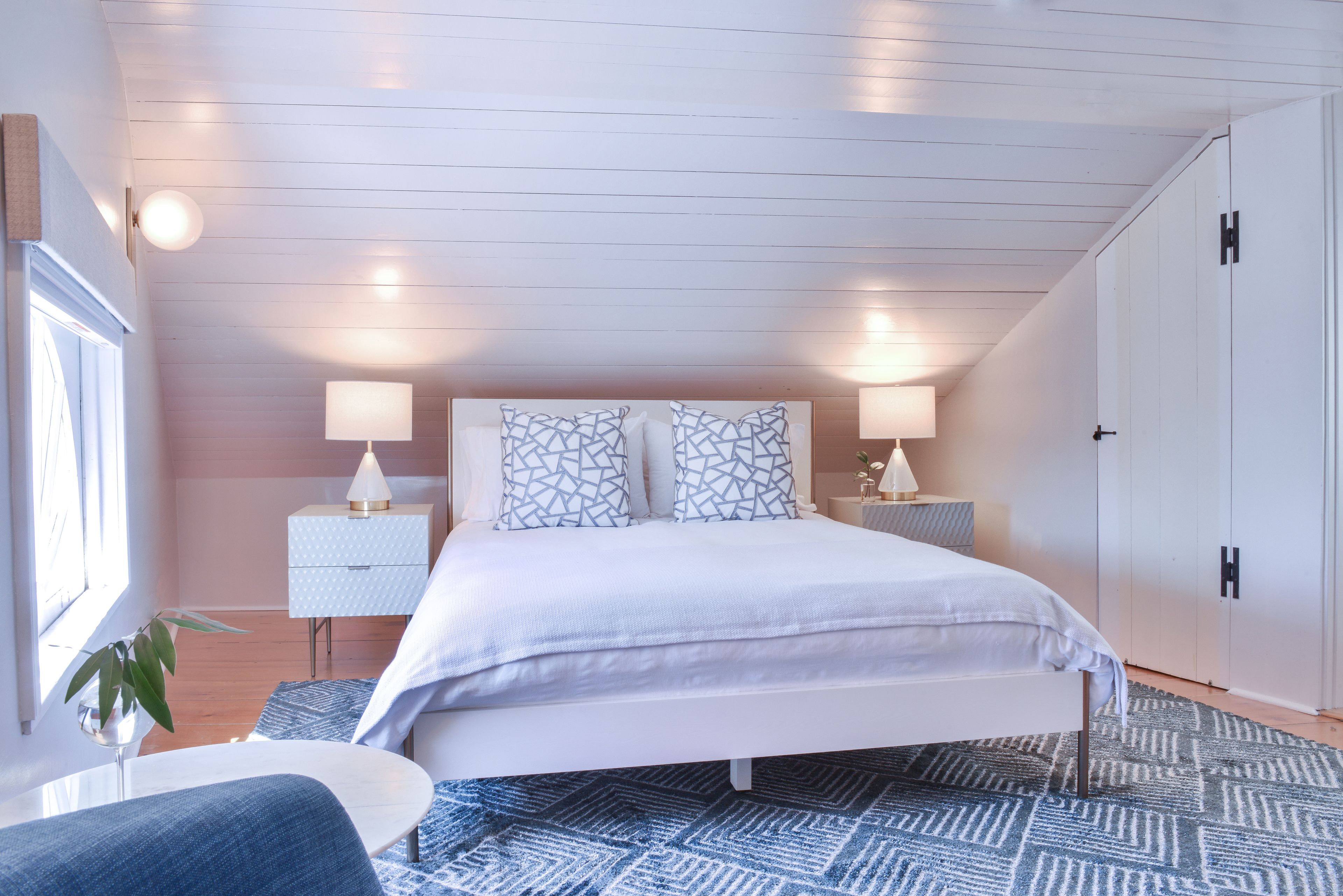 A bedroom with a bed, bedside tables, a wardrobe, and a window.