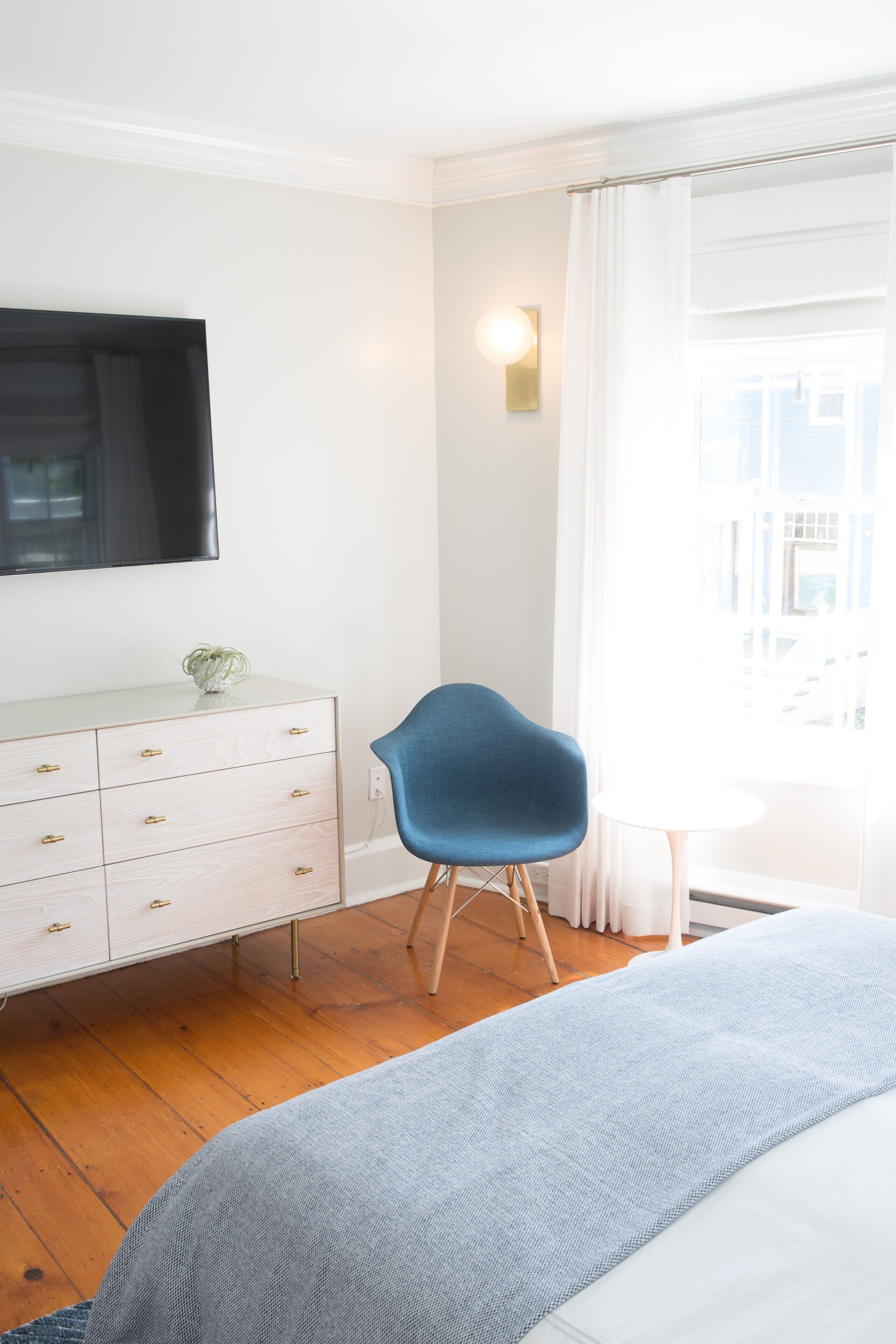 A bedroom with a bed, a dresser, a chair, and a window with curtains.