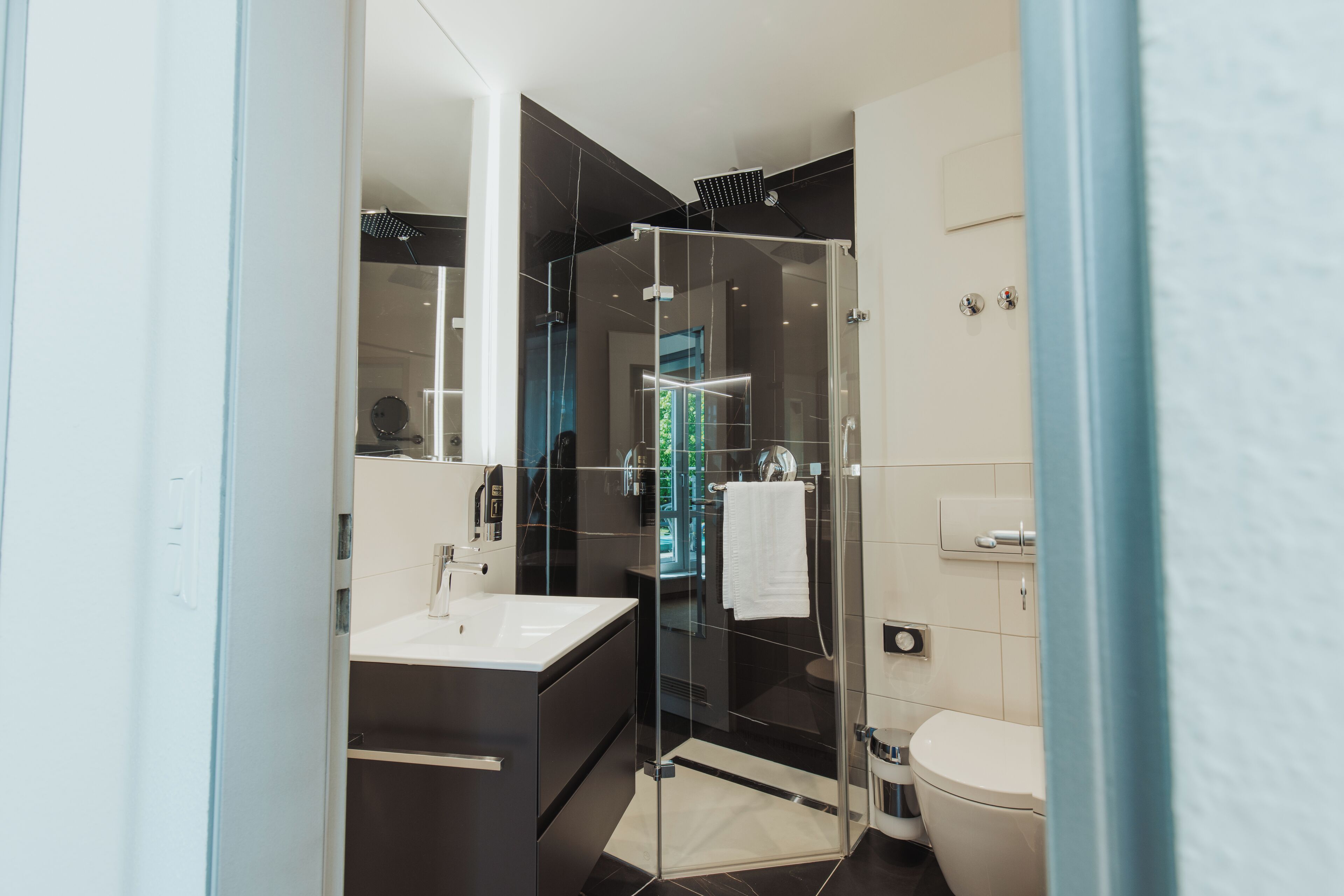 Une salle de bain moderne avec une douche à parois de verre, un lavabo blanc et des toilettes.