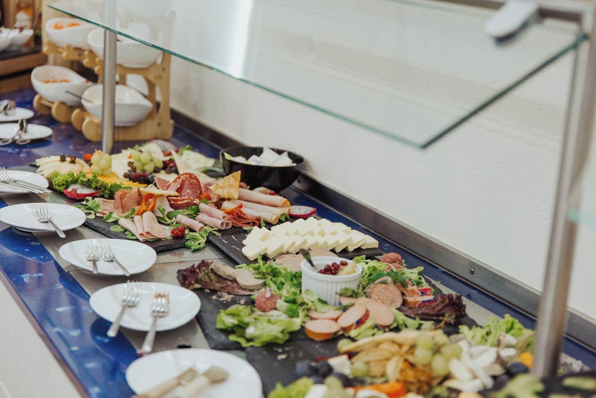 Un bufé con diversos alimentos, incluyendo carnes, quesos y ensaladas.