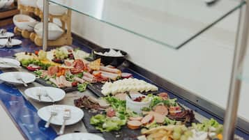 Un bufé con diversos alimentos, incluyendo carnes, quesos y ensaladas.
