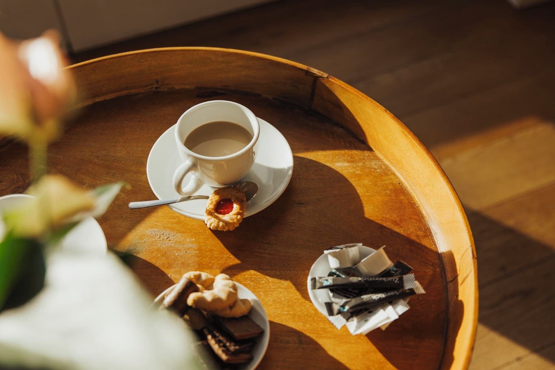 Ein Holztablett mit einer Tasse Kaffee, einem Gebäck und einer kleinen Schale Schokolade.
