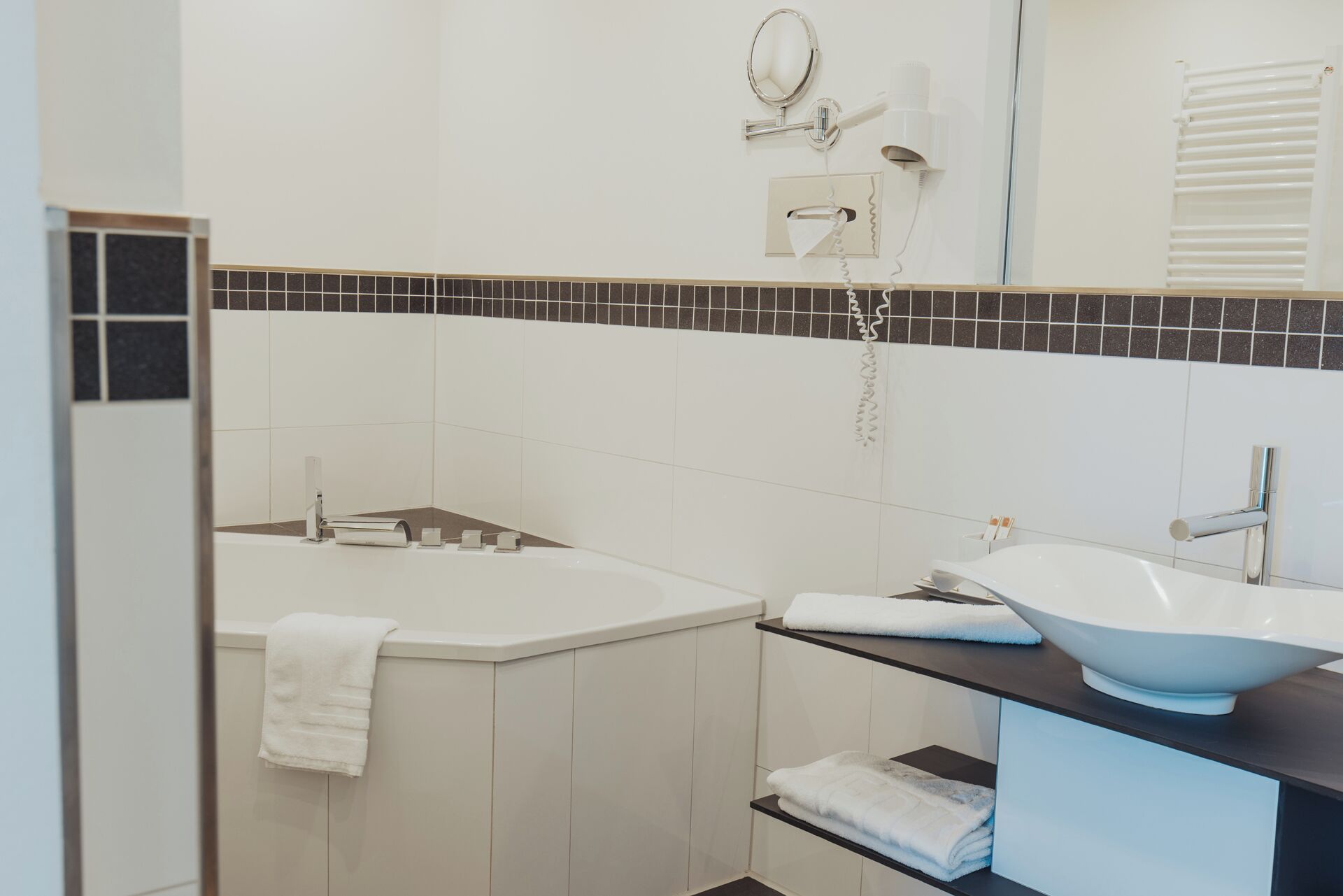 Ein modernes Badezimmer mit einer weißen Badewanne, einem Waschbecken und einem Spiegel.