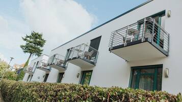 A modern building with multiple balconies, each with a metal railing and a small table.