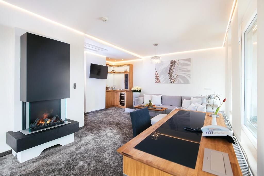 Una sala de estar moderna con chimenea, un comedor y una cocina al fondo.