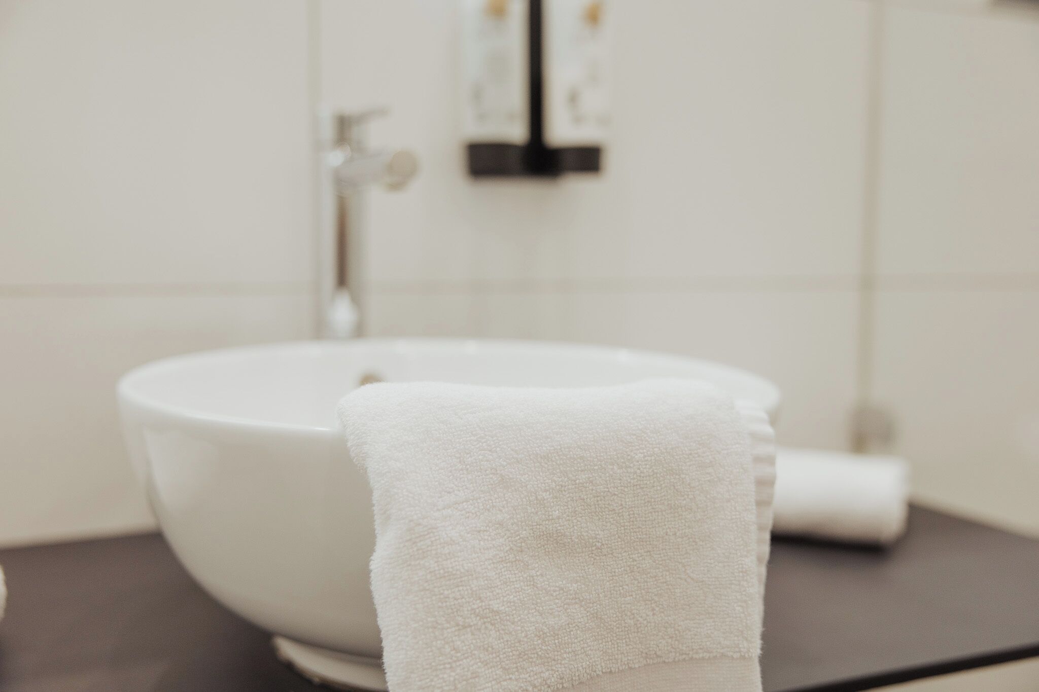 Ein Badezimmer mit einem weißen Waschbecken, einem Handtuch und einer schwarzen Arbeitsplatte.