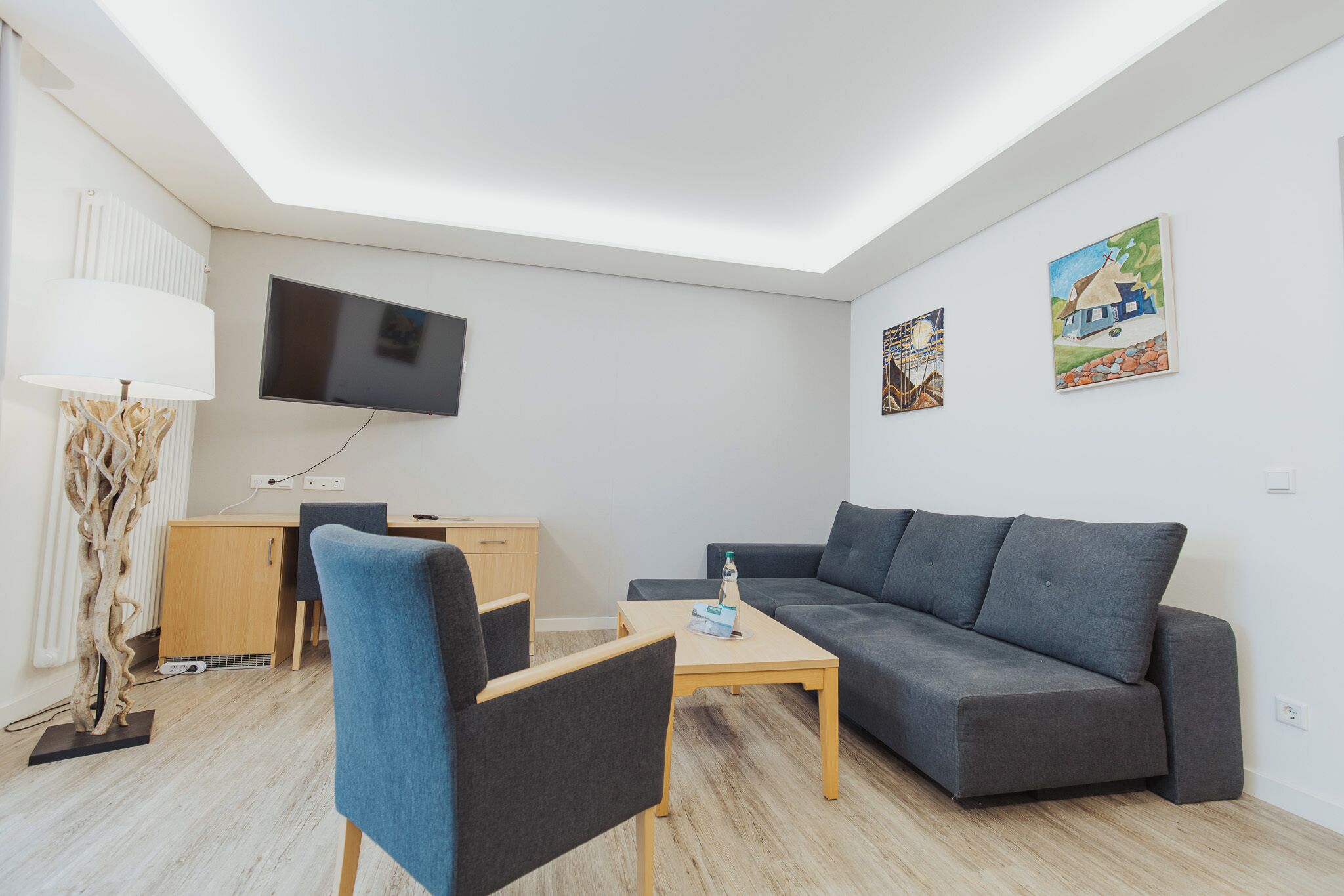 A modern living room with a sofa, a coffee table, a TV, and artwork on the wall.