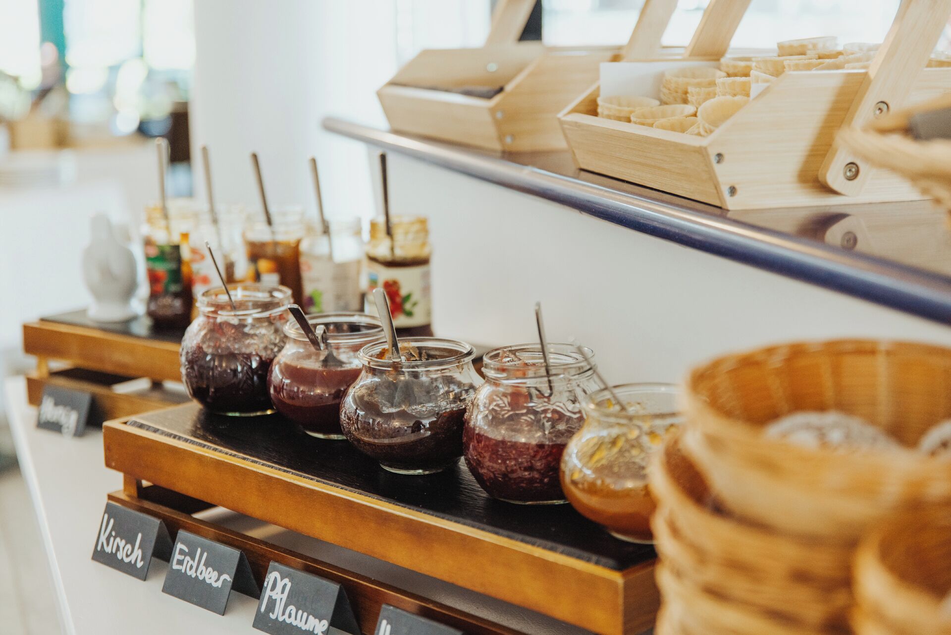 A beverage station with various drinks in jars and a wooden display of pastries.