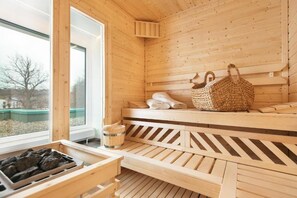 A wooden sauna with benches, a woven basket, and towels. - Parkhotel IV Jahreszeiten Kühlungsborn (Kuehlungsborn)