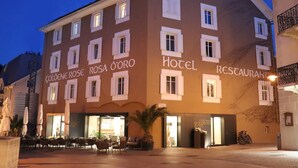 Un hotel con letrero que dice "Golden Rose Rosa O'oro", asientos al aire libre y una entrada visible.