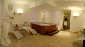 A spa room with a hot tub, reclining chairs, and a statue.